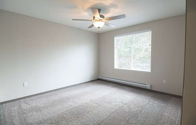 an empty room with a ceiling fan and a window