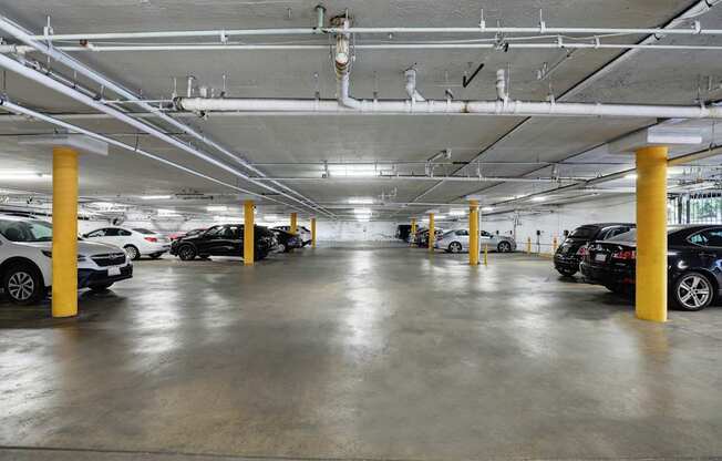 A parking garage with cars parked and yellow poles.