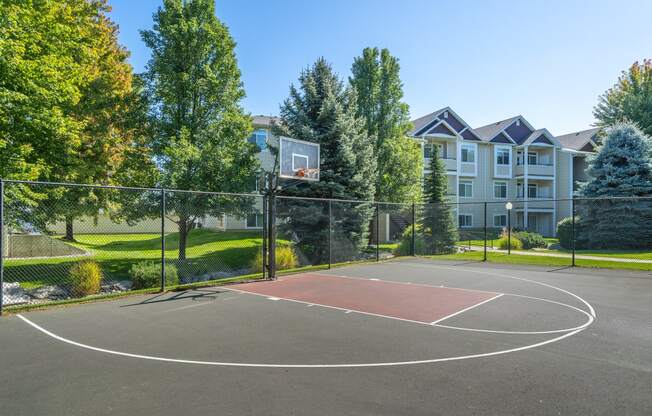 a basketball court with trees and a building in the background