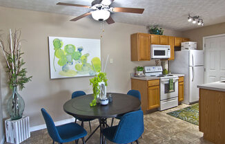 A kitchen with a table and chairs in the foreground and a painting on the wall.