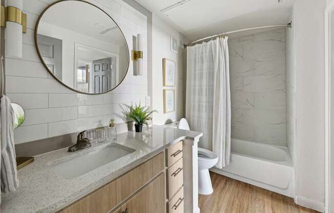 A bathroom with a sink, mirror, and shower.