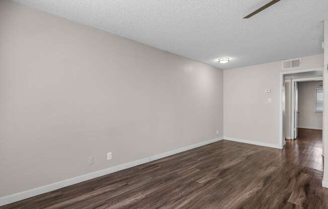 an empty living room with wood flooring and white walls