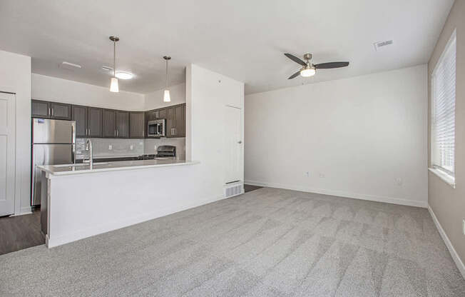 A living room with a carpeted floor and a ceiling fan at Meadowbrooke Apartment Homes in Kentwood, MI 49512