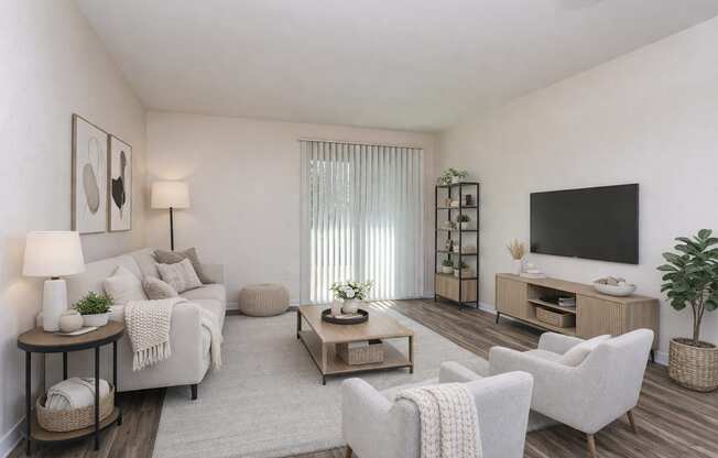 A living room with a white couch, a wooden coffee table, and a flat-screen TV mounted on the wall.