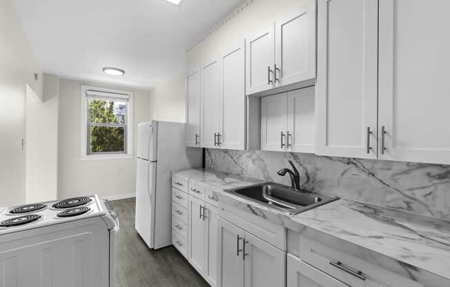 Spacious kitchen with white cabinetry, plank flooring, and marble look countertops at Stockbridge Apartment Homes, Washington