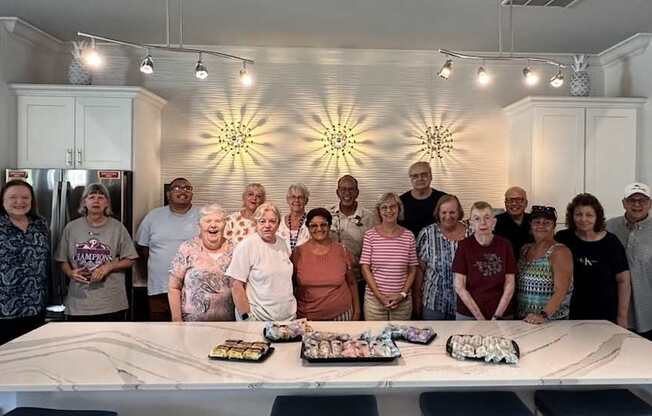A group of people are gathered around a table with a cake in the middle.