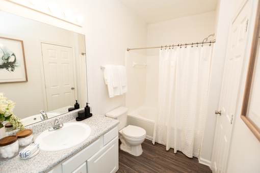 A white bathroom with a toilet, sink, and shower.