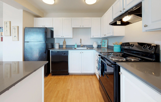Renton WA Apartments - Sunset View - Kitchen with White Cabinets, Black Appliances, Wood Style Flooring, and Grey Countertops