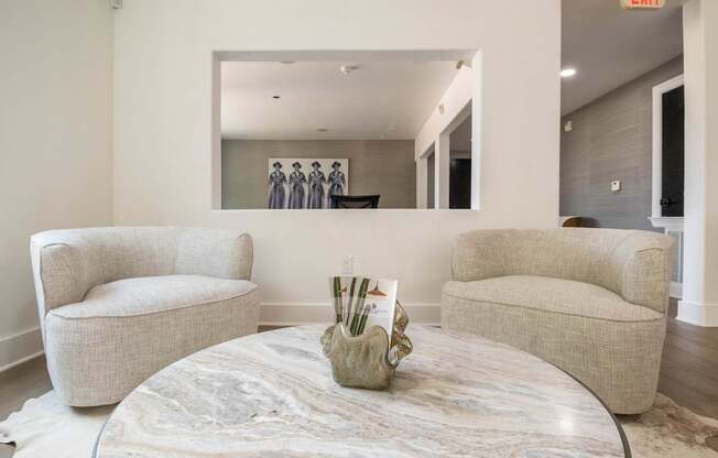 A living room with a round marble table and two chairs.