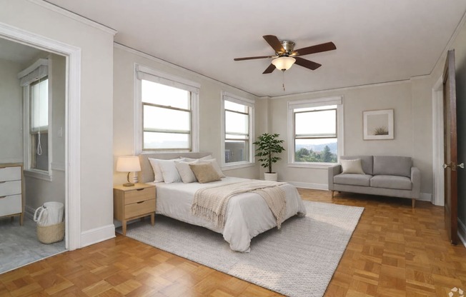 A bedroom with a bed, a couch, a ceiling fan, and a rug.