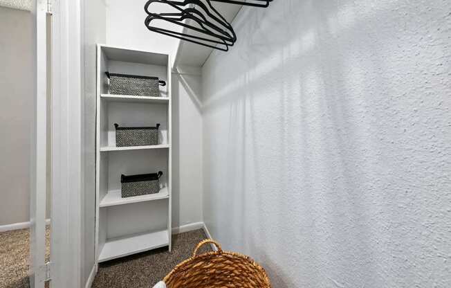 A white shelving unit with a basket on the floor.