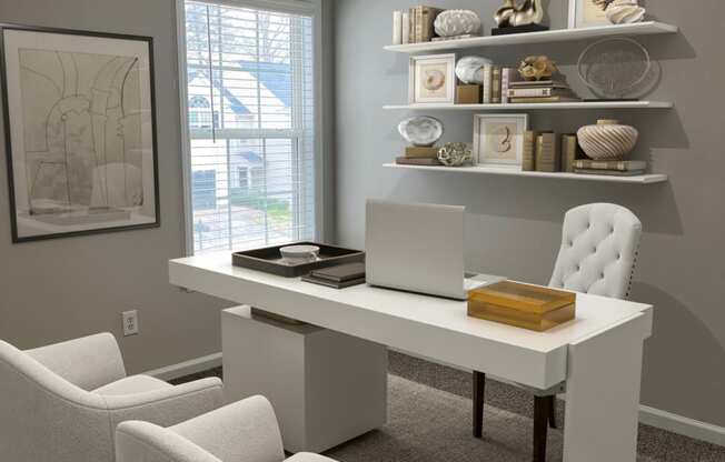 a home office with a white desk and chairs and a laptop