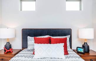 A bed with a blue headboard and red and white pillows is in the image.