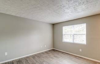 A room with a window and wooden flooring.