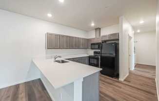 a kitchen with a white counter top and a black refrigerator at Gateway Apartments, Washington