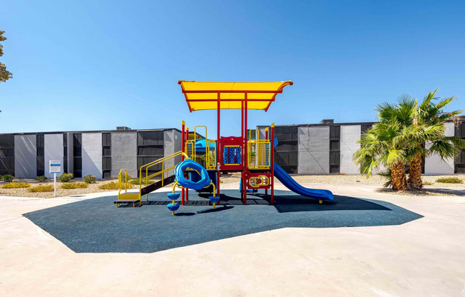 a colorful playground in front of a building with palm trees