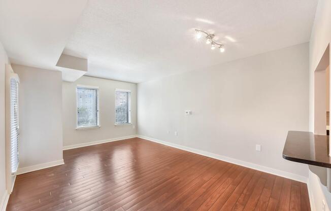 A room with wooden flooring and a window with blinds.