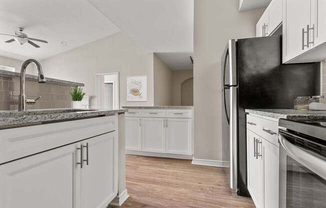 A kitchen with white cabinets and a black refrigerator.