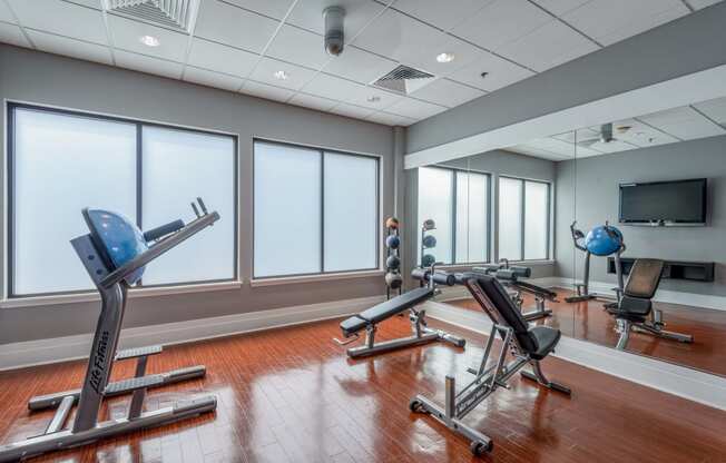 a fitness room with exercise machines and windows