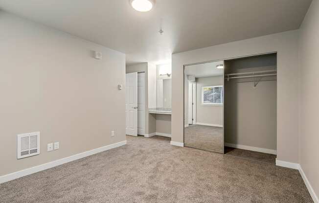 One-Bedroom Apartments in Tukwila, WA - Foster Creek - Unfurnished Bedroom with Carpet, Mirrored Closet, and Built-In Vanity with Mirror