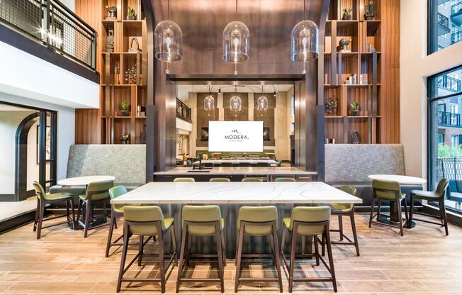 Community demonstration kitchen with a marble island, bar seating, and arched wood detailing designed for hosting, shared meals, and everyday connection.