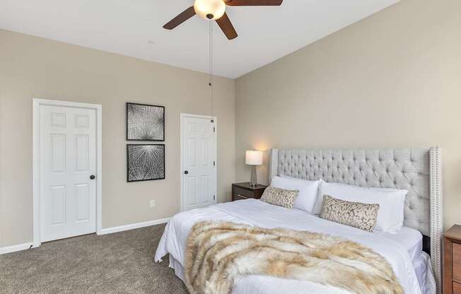 A bedroom with a large bed and a ceiling fan.