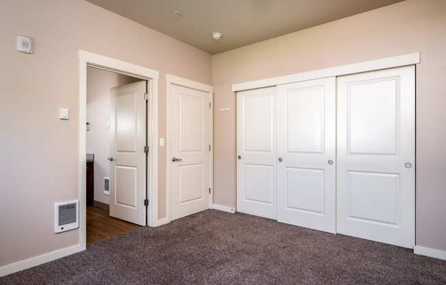 a bedroom with three doors and a carpeted floor