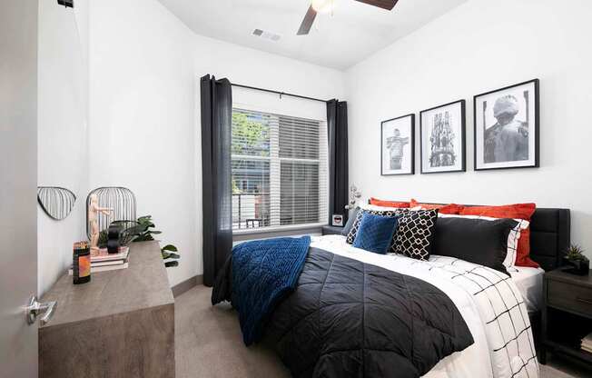 A bedroom with a bed, a nightstand, and a window with curtains.