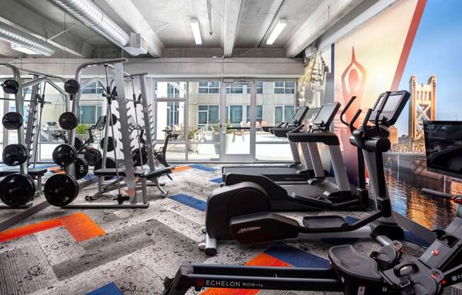 a gym with weights and cardio equipment in a room with a large window