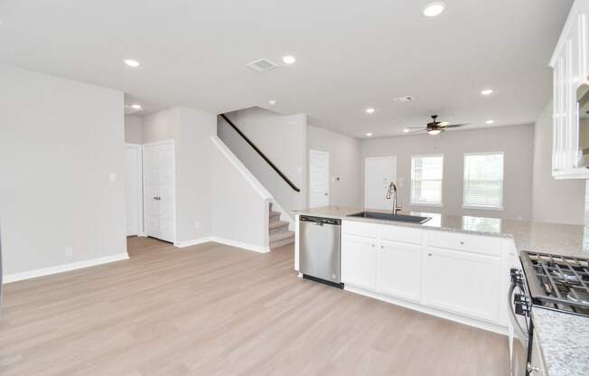 a kitchen and living room with white walls and a wooden floor