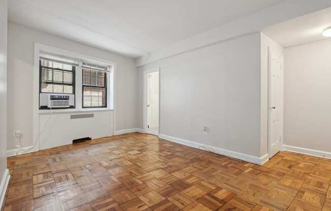 a bedroom with a large window and hardwood floors