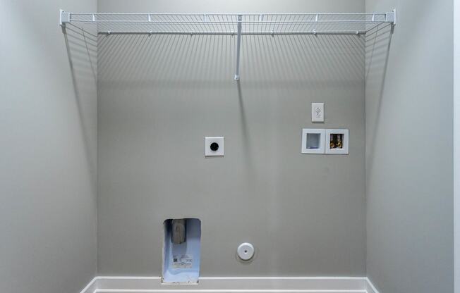 a closet with a wire shelving unit on top of it and a toilet paper dispenser