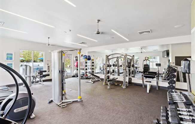 A gym with a variety of equipment including treadmills, weights, and exercise machines.
