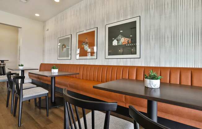 a dining room with orange booths and black tables and chairs at Aventura at Hawk Ridge, Lake St Louis, MO 63367