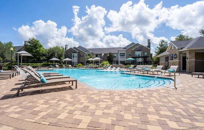 A large swimming pool surrounded by lounge chairs and umbrellas.