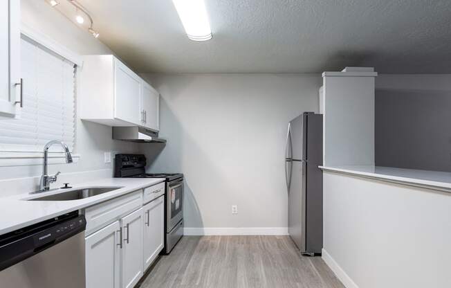 A kitchen with white cabinets and a black dishwasher.
