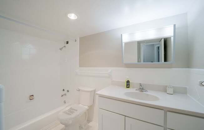 A white bathroom with a toilet, sink, and mirror.
