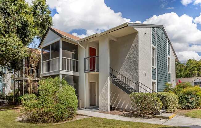 A two-story house with a red door and a balcony.