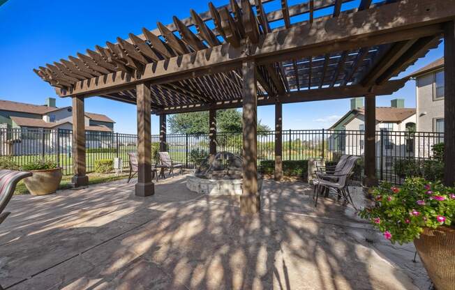 a patio with a wooden pergola and a fire pit