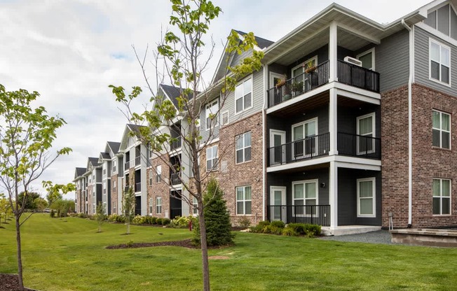 Apartment building with balconies and trees in front.