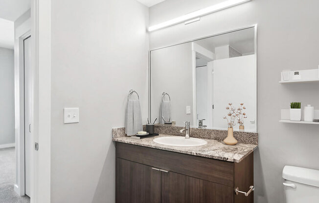 Model Bathroom with Wood-Style Flooring and Dark Oak Cabinets at Seven Skies Apartments located in Sandy, UT.