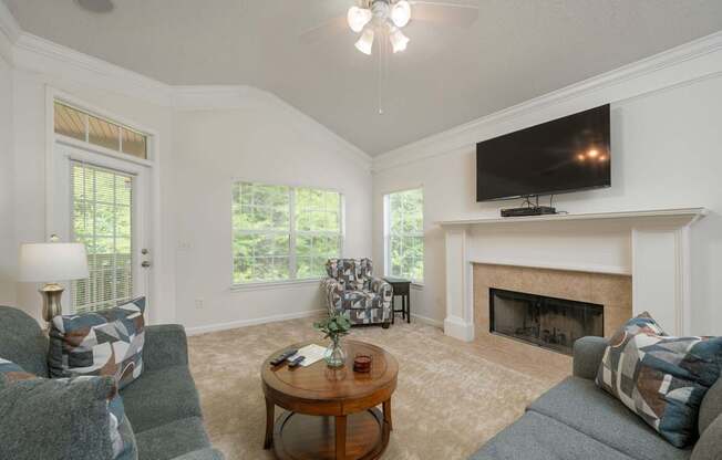 A living room with a fireplace and a television mounted above it.