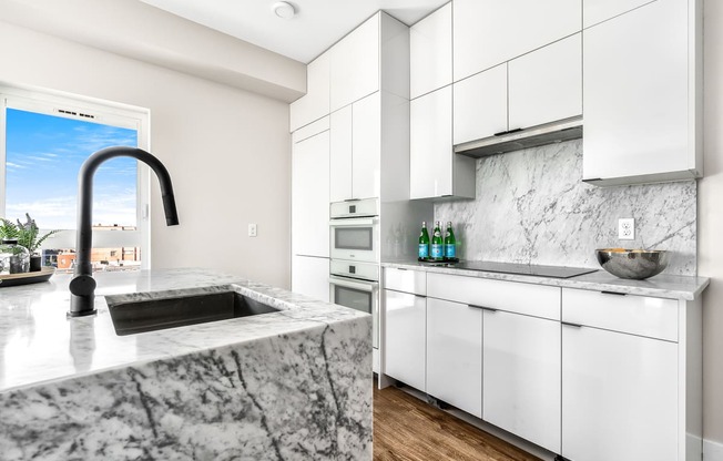 a kitchen with white cabinets and marble counter tops and a sink  at Oslo, Seattle, 98102