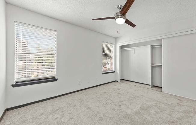 A room with a ceiling fan and a window with blinds.