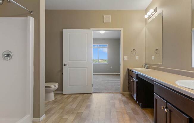 A bathroom with a white toilet, a white door, and a wooden floor.