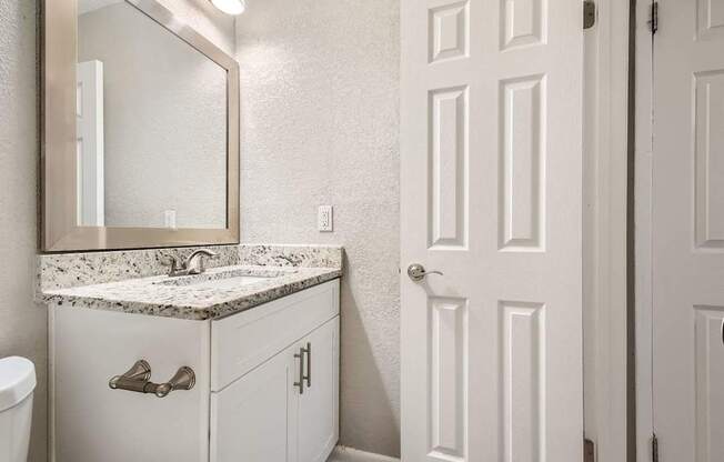 A bathroom with a sink, mirror, and toilet.