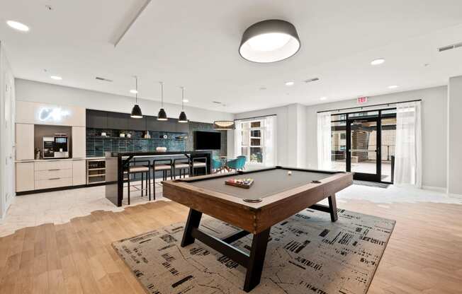 a living room with a pool table and a kitchen with a bar