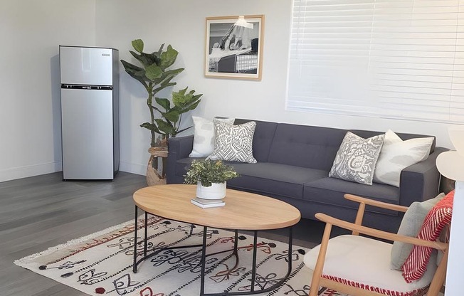 A living room with a grey couch, a wooden coffee table, and a ceiling fan.