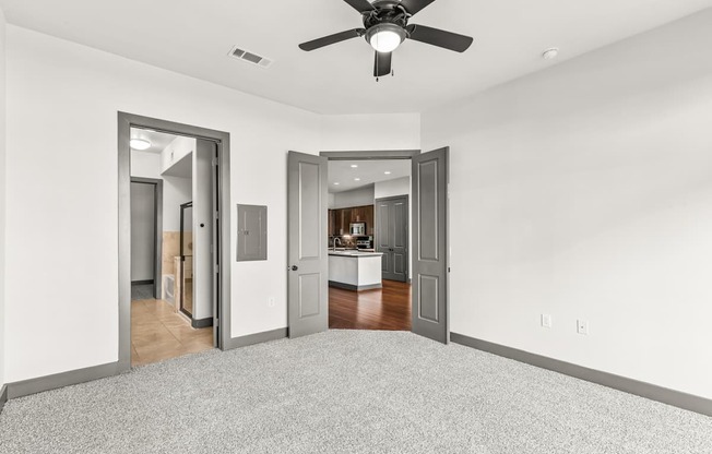 A room with a ceiling fan and two open doors.