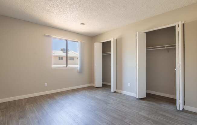 an empty bedroom with a closet and a window